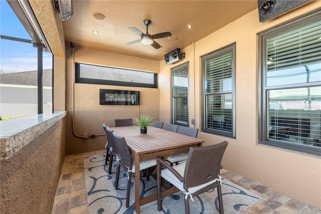 view of patio with a ceiling fan, outdoor dining area, and glass enclosure