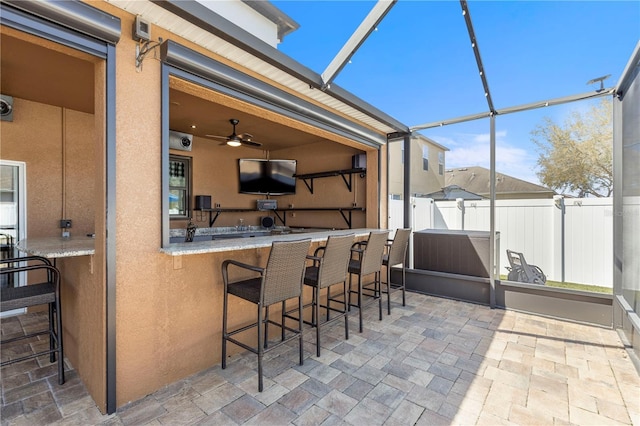 view of patio featuring a lanai, fence, and exterior bar