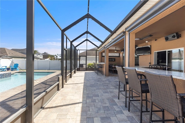 view of patio featuring a fenced in pool, outdoor dry bar, a ceiling fan, glass enclosure, and fence