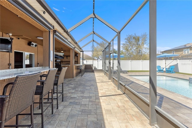 view of patio featuring a lanai, a fenced backyard, a fenced in pool, and outdoor wet bar