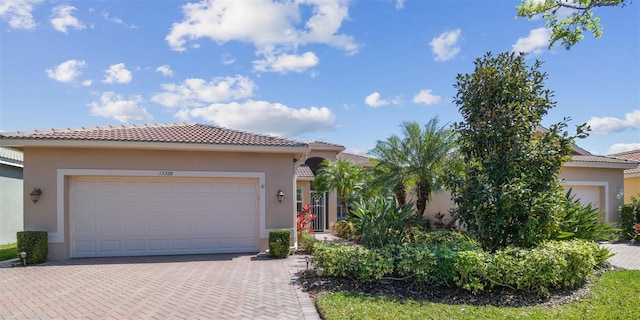 view of front of property with a garage, decorative driveway, a tile roof, and stucco siding