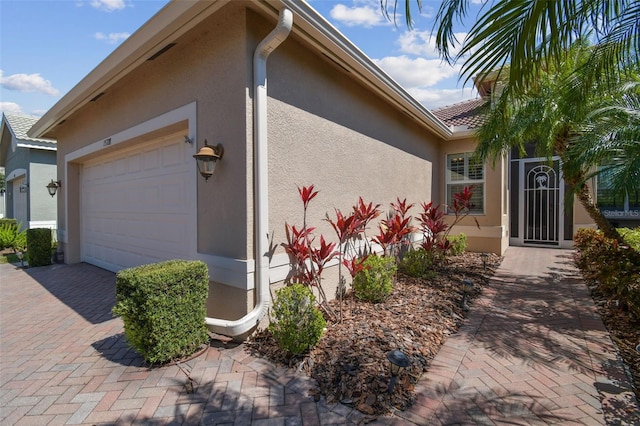 view of property exterior featuring a garage, decorative driveway, and stucco siding