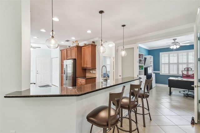 kitchen featuring pendant lighting, brown cabinets, stainless steel refrigerator with ice dispenser, light tile patterned floors, and ornamental molding