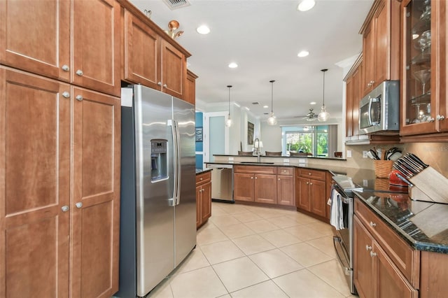 kitchen with stainless steel appliances, a peninsula, a sink, and brown cabinets