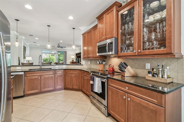 kitchen with dark stone counters, appliances with stainless steel finishes, a sink, and brown cabinets