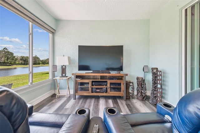 living area featuring a textured ceiling, a textured wall, wood finished floors, and baseboards