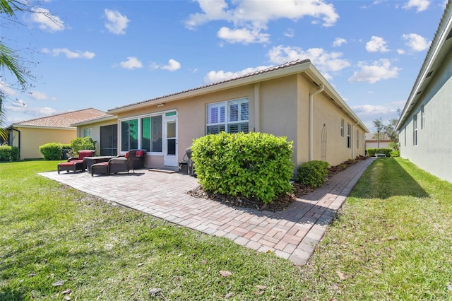 rear view of house featuring stucco siding, a lawn, and a patio