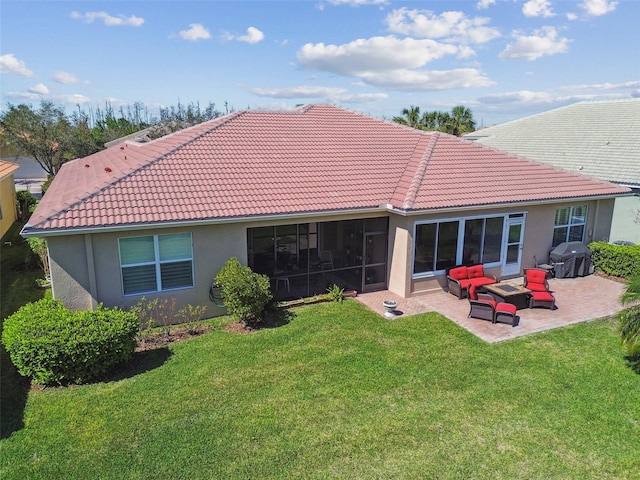 rear view of house featuring a sunroom, a tiled roof, a yard, a patio area, and stucco siding