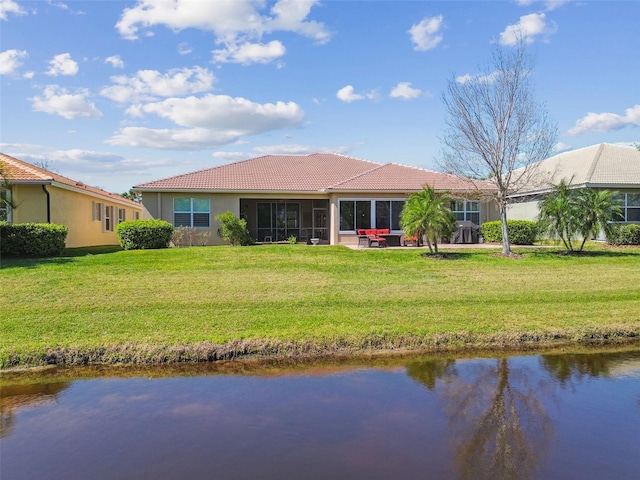 back of house with a lawn, a water view, a tile roof, and a sunroom