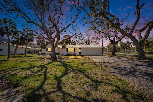 view of front facade featuring driveway, metal roof, and a front lawn