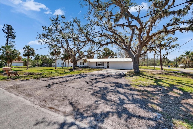 view of front facade featuring a garage, a front lawn, and gravel driveway