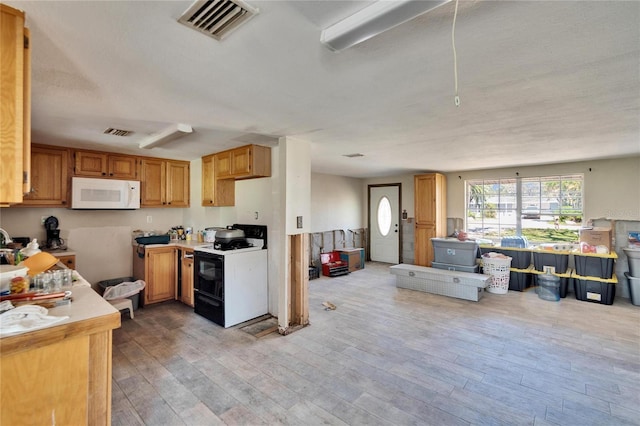 kitchen with light countertops, light wood-type flooring, white appliances, and visible vents