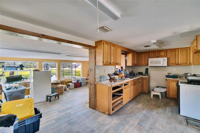 kitchen with white appliances, light wood-style flooring, visible vents, and light countertops