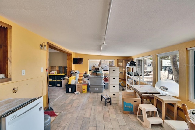 interior space featuring light wood-style floors, refrigerator, and a textured ceiling