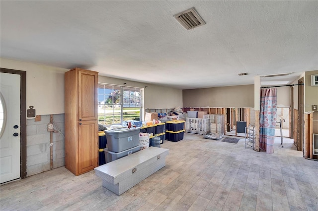 interior space with light wood-style floors, visible vents, and a textured ceiling