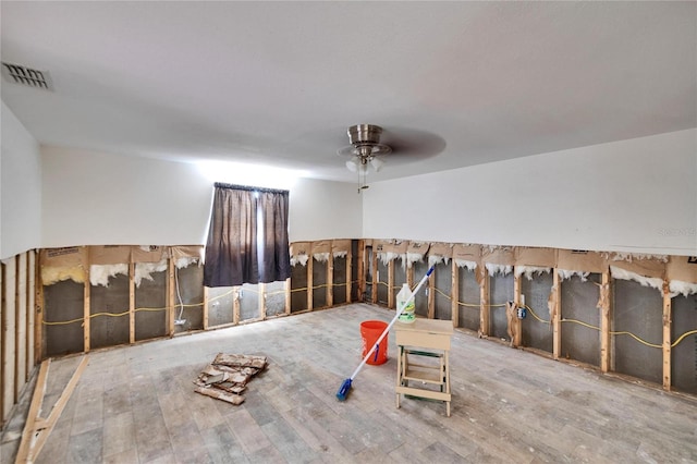 interior space with a ceiling fan, visible vents, and wood finished floors