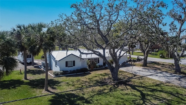 view of front of property featuring metal roof, a front lawn, and concrete driveway