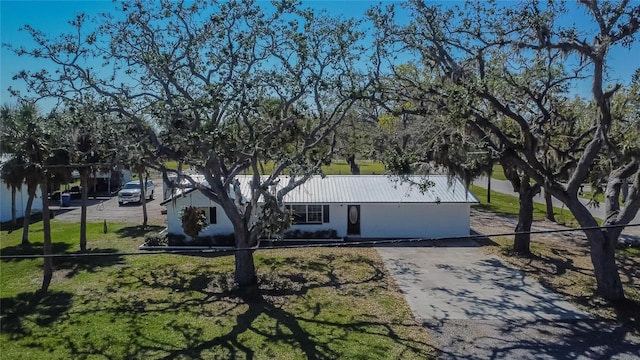 view of front facade featuring a front yard, metal roof, and driveway