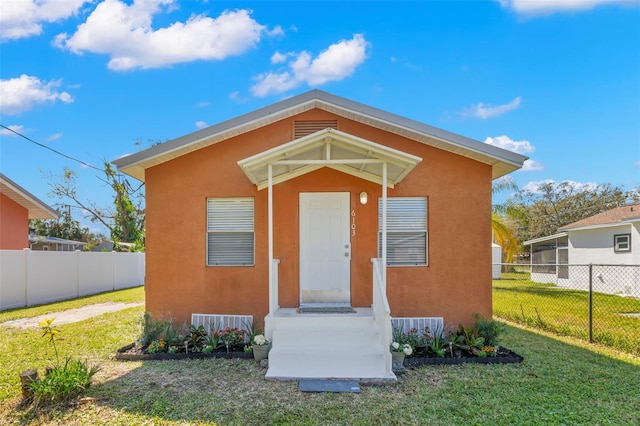 view of front of property featuring a front yard, fence, and stucco siding