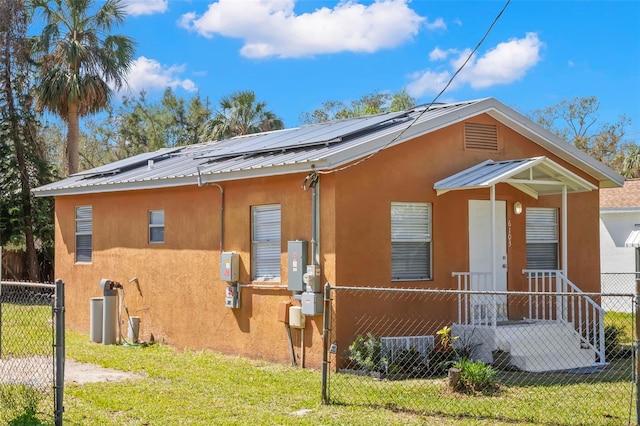 exterior space with roof mounted solar panels, metal roof, fence, and stucco siding