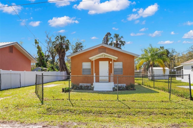 view of front of home with a front yard, a fenced backyard, and stucco siding