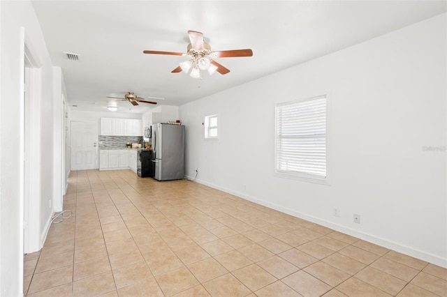 unfurnished living room featuring baseboards, visible vents, a ceiling fan, and light tile patterned flooring