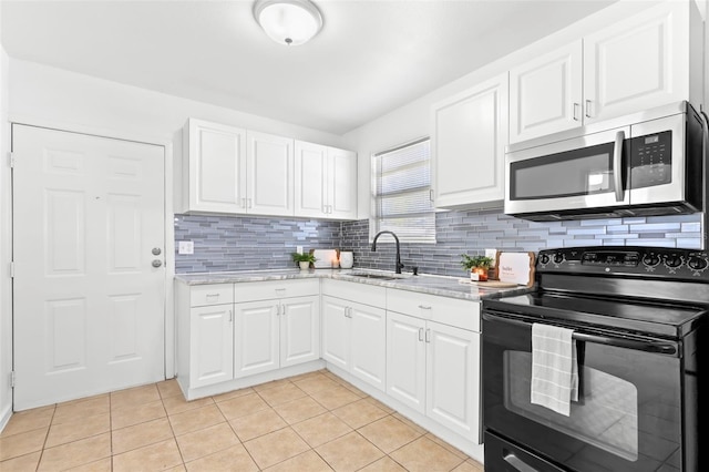 kitchen featuring black / electric stove, light tile patterned flooring, a sink, tasteful backsplash, and stainless steel microwave