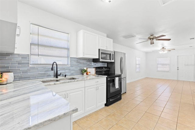 kitchen featuring appliances with stainless steel finishes, white cabinets, a sink, and light tile patterned floors