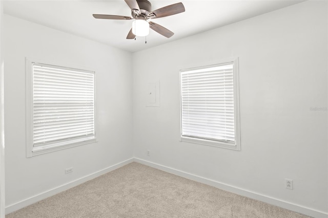 carpeted spare room featuring baseboards and a ceiling fan