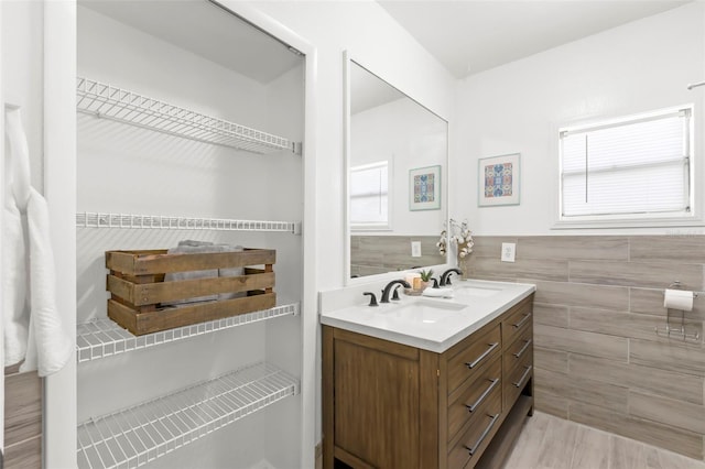 full bathroom featuring wainscoting, a sink, tile walls, and double vanity