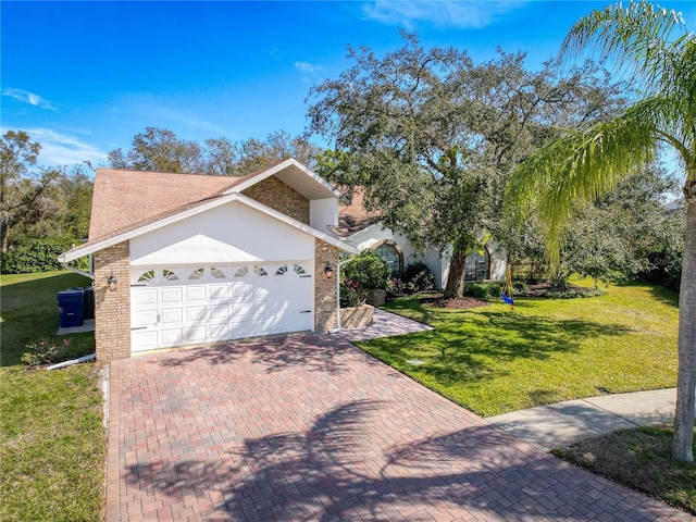 view of front of home with stucco siding, an attached garage, decorative driveway, a front yard, and brick siding