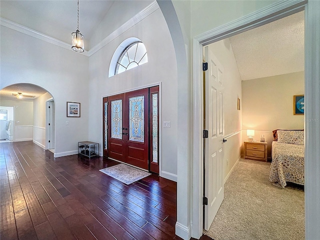 foyer featuring arched walkways, baseboards, a healthy amount of sunlight, and hardwood / wood-style floors