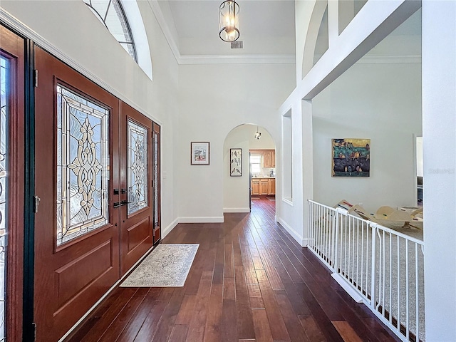 foyer entrance featuring arched walkways, dark wood-style flooring, a healthy amount of sunlight, and baseboards