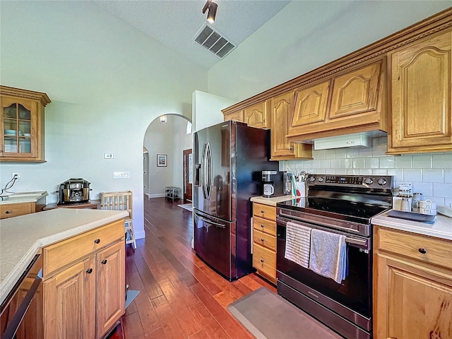 kitchen featuring arched walkways, stainless steel electric range oven, light countertops, black fridge with ice dispenser, and visible vents