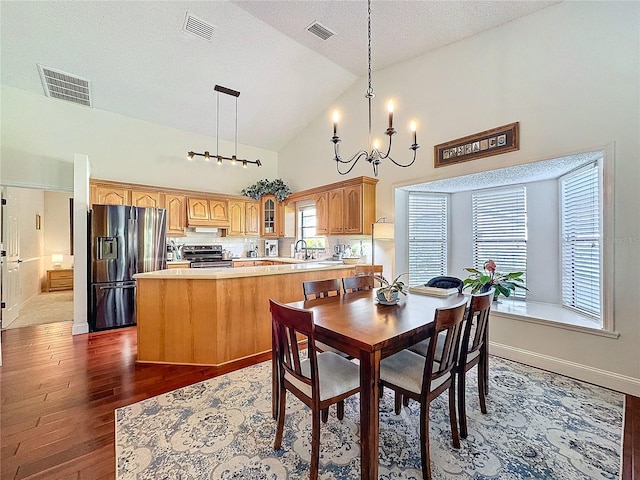 dining room with dark wood-type flooring, visible vents, high vaulted ceiling, and an inviting chandelier