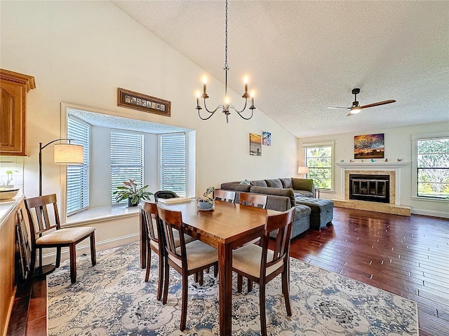 dining space with a textured ceiling, dark wood-type flooring, plenty of natural light, and a glass covered fireplace