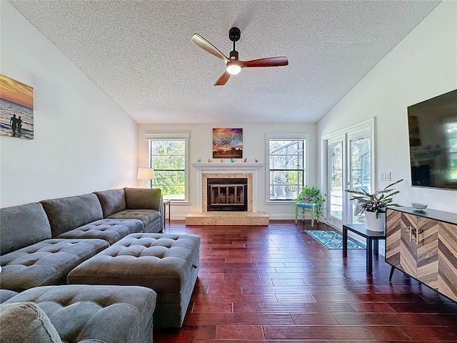 living area featuring a healthy amount of sunlight, lofted ceiling, dark wood-style flooring, and a glass covered fireplace