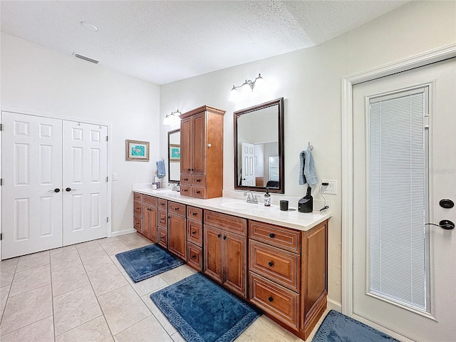 bathroom featuring double vanity, a textured ceiling, visible vents, and a sink