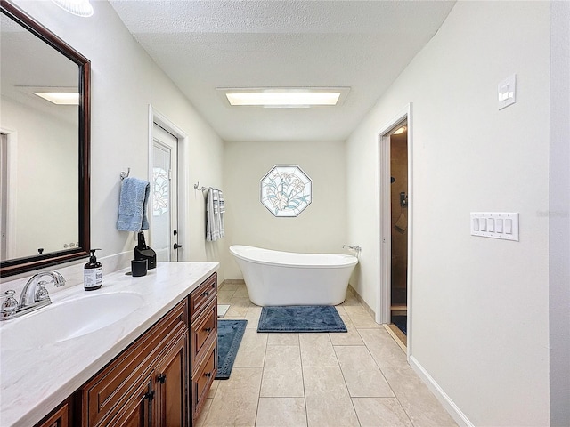 bathroom featuring a textured ceiling, vanity, baseboards, a soaking tub, and tile patterned floors