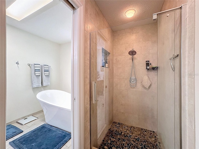 full bathroom featuring a stall shower, a freestanding bath, and a textured ceiling