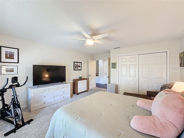 carpeted bedroom featuring a textured ceiling, ceiling fan, a closet, and visible vents