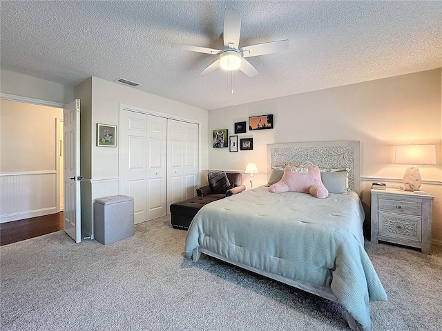 bedroom with a closet, wainscoting, carpet flooring, and visible vents