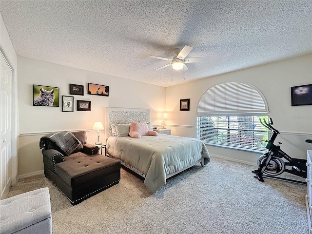 carpeted bedroom with ceiling fan, a textured ceiling, and baseboards