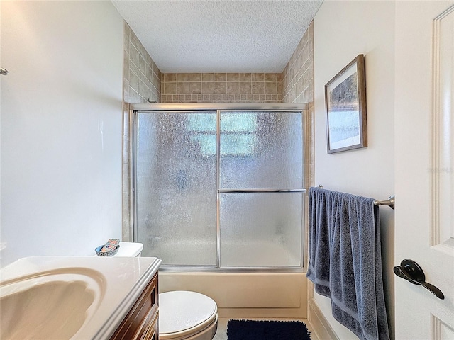 bathroom featuring a textured ceiling, shower / bath combination with glass door, toilet, and a healthy amount of sunlight