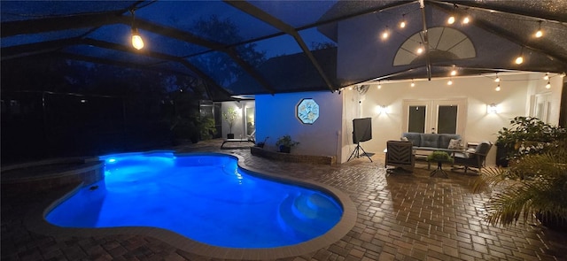 pool at night with french doors, a patio, outdoor lounge area, a lanai, and an outdoor pool