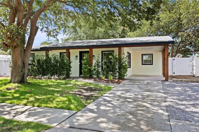 view of front of property featuring stucco siding, concrete driveway, a gate, an attached carport, and covered porch