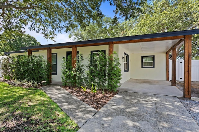 view of front of property featuring an attached carport, stucco siding, and fence