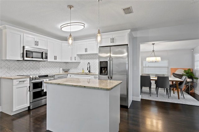 kitchen with stainless steel appliances, a sink, dark wood-style flooring, and decorative backsplash