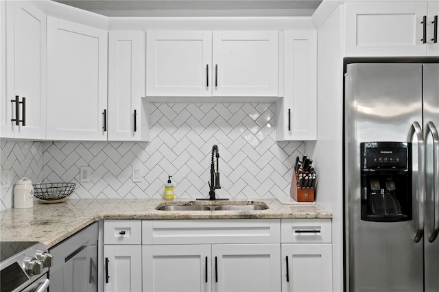 kitchen featuring stainless steel appliances, a sink, tasteful backsplash, and white cabinets