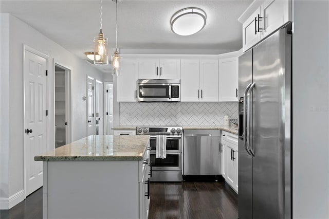 kitchen with appliances with stainless steel finishes, decorative backsplash, a kitchen island, and dark wood-style floors